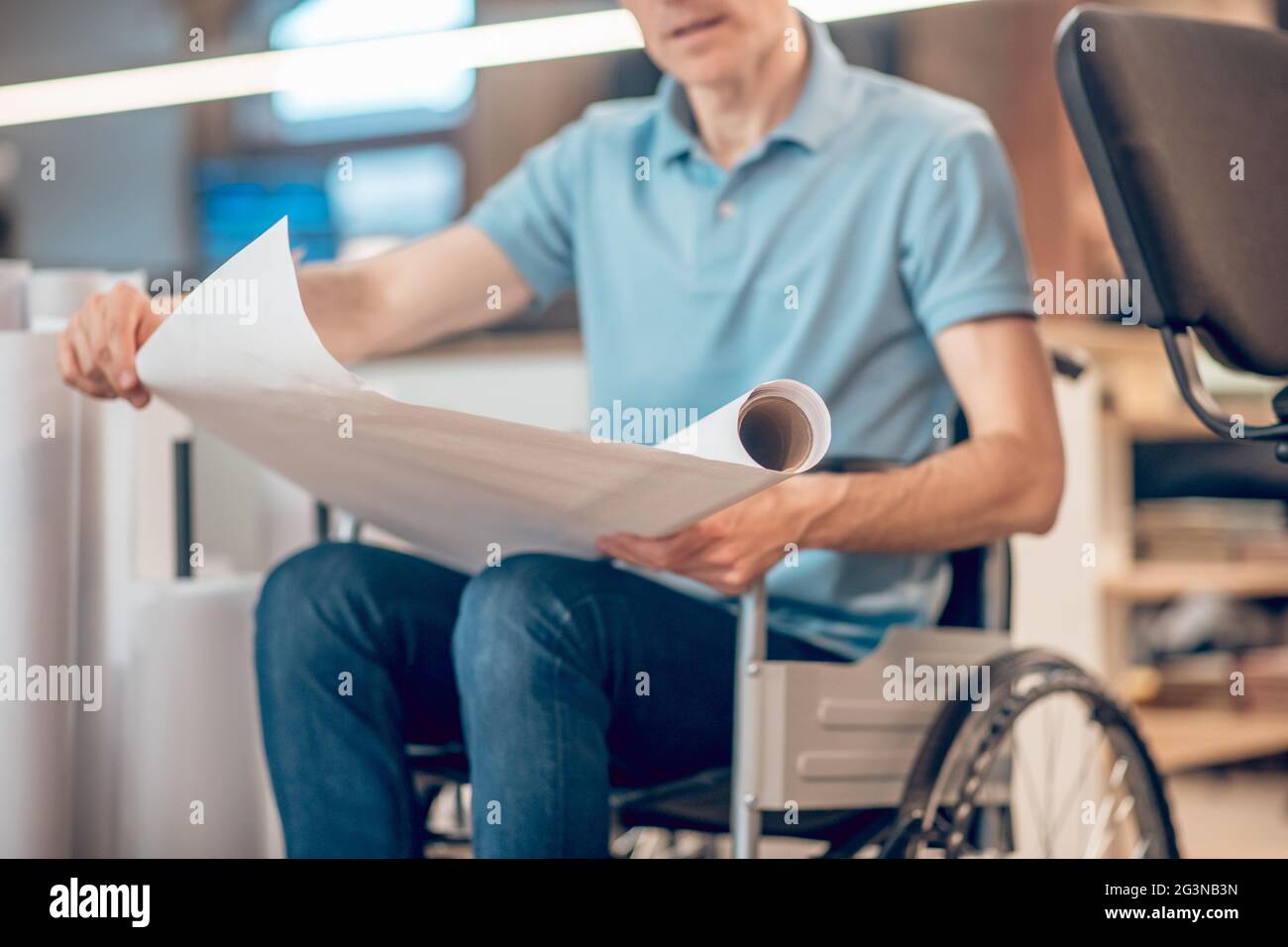 Roll of paper in hands of man on wheelchair Stock Photo