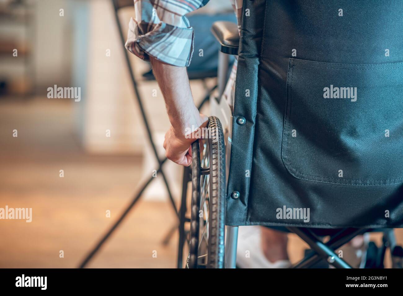 Male hand on wheelchair wheel indoors Stock Photo Alamy