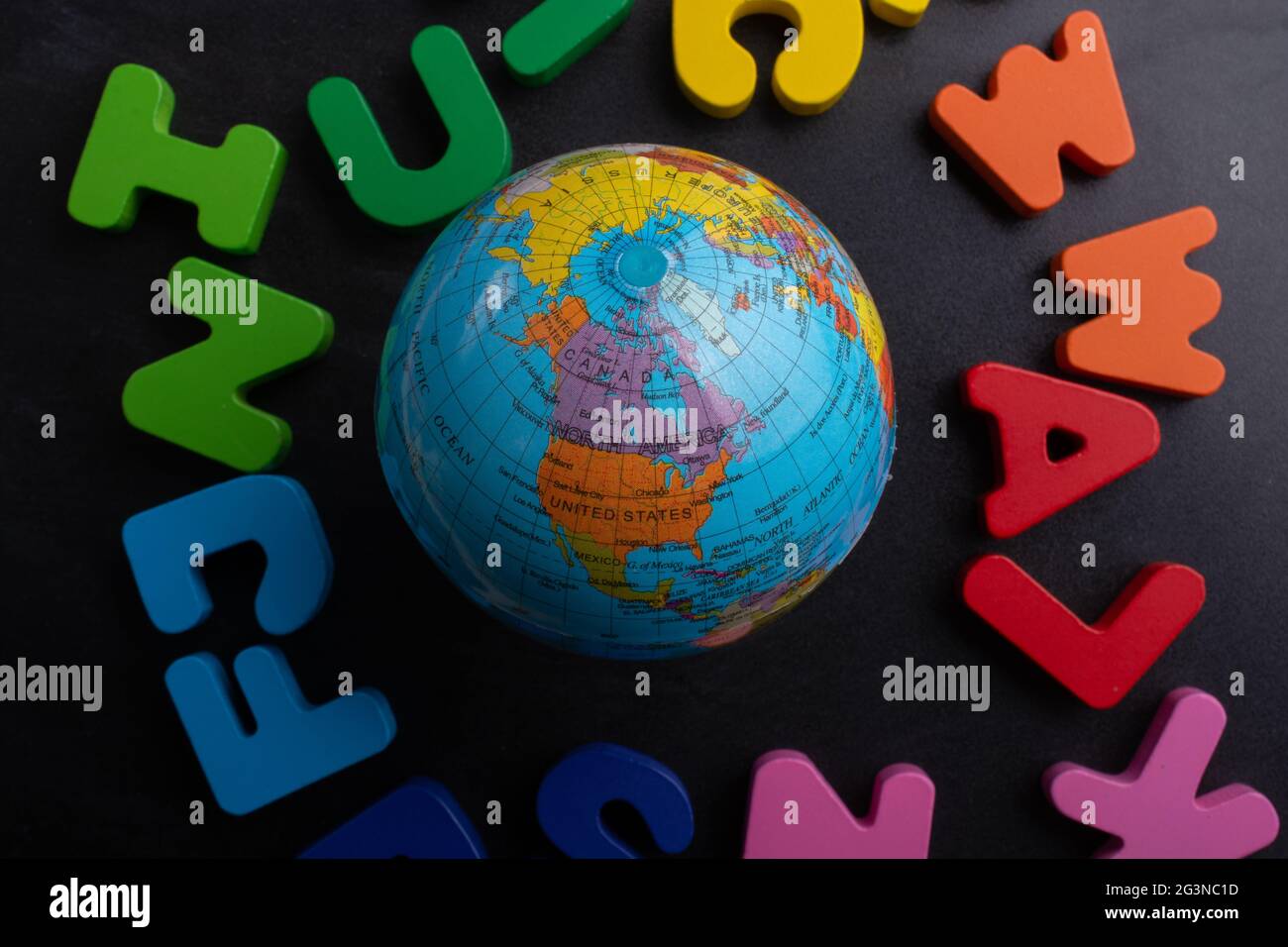 Globe model on colorful letters on a black background Stock Photo