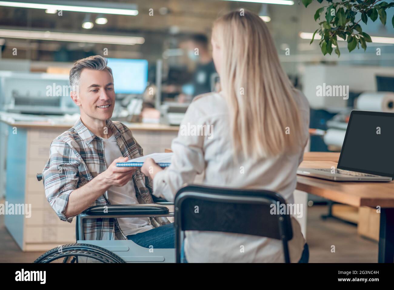 Man in wheelchair and woman with back to camera Stock Photo