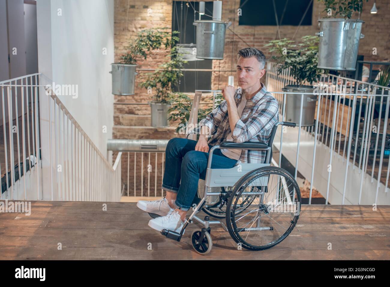 Man on wheelchair in despair near stairs Stock Photo