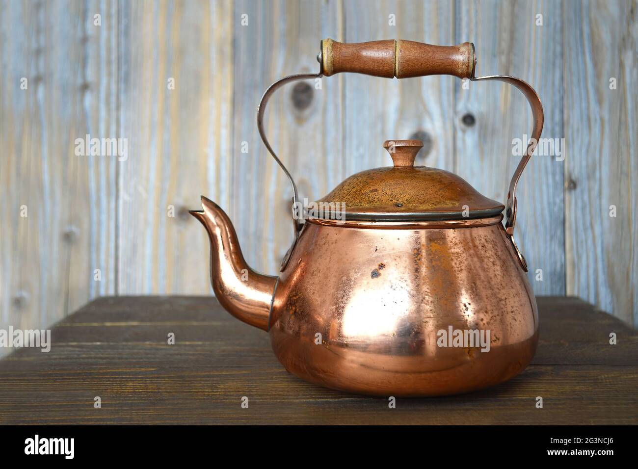 Old copper teapot on wooden background Stock Photo