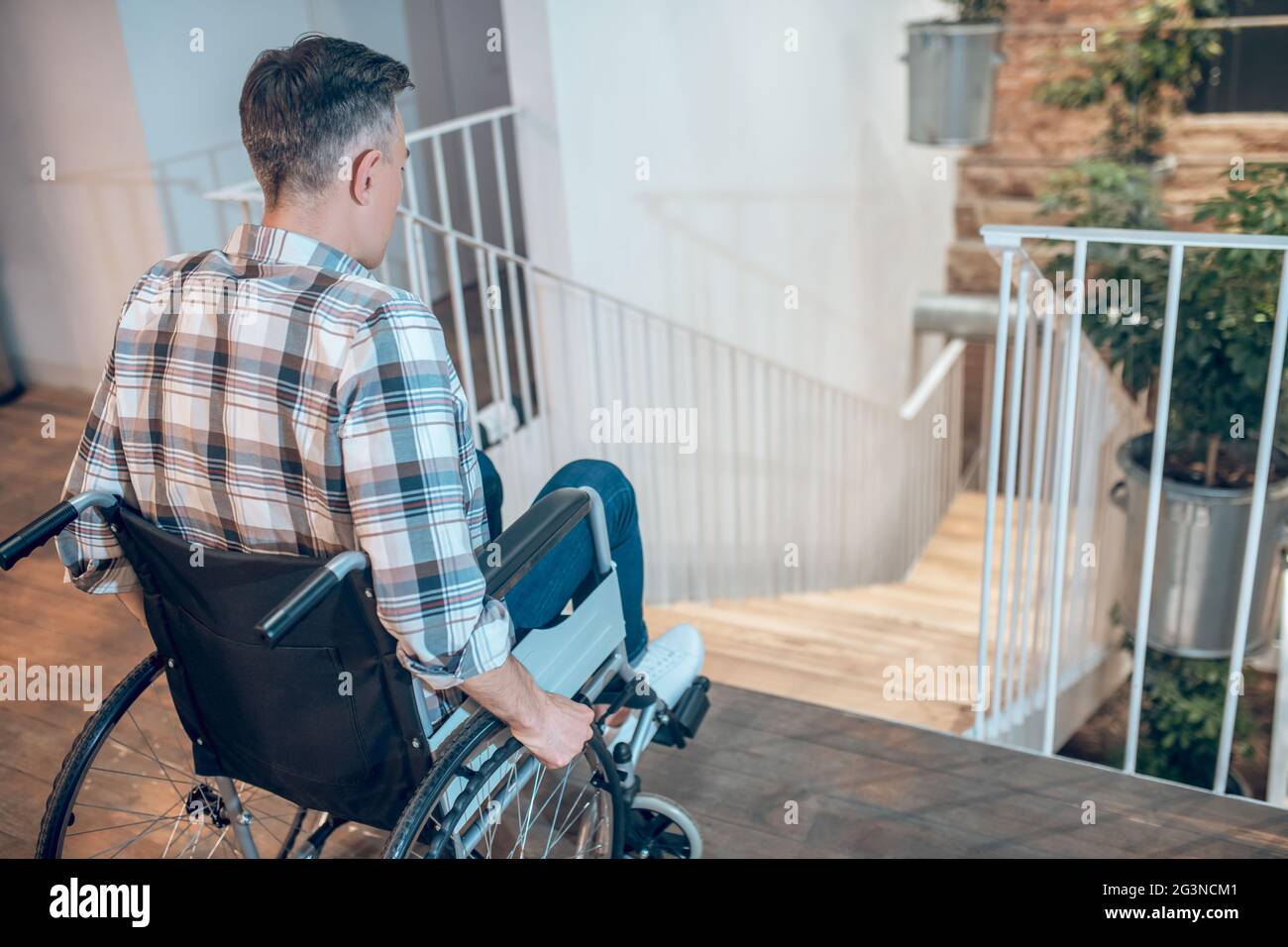 View back of a man in wheelchair near stairs Stock Photo