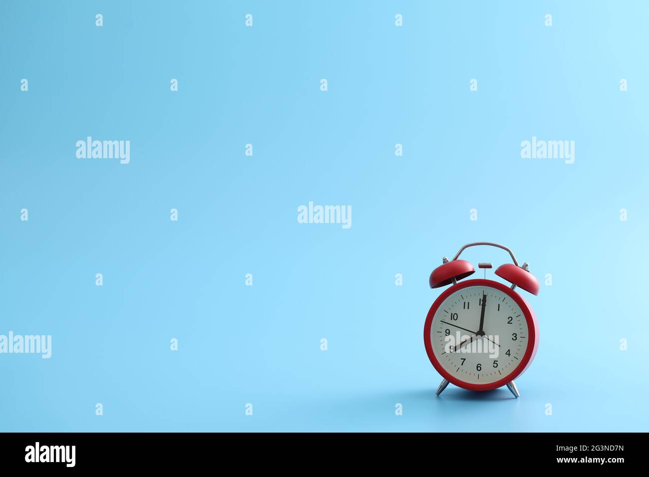 Red retro alarm clock isolated on a blue background Stock Photo - Alamy