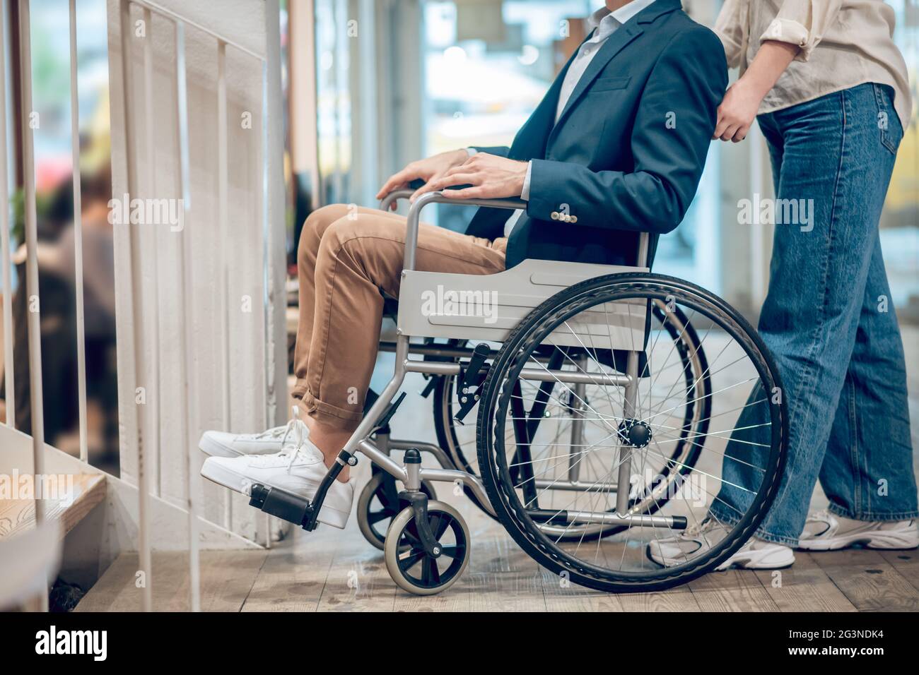 Man in wheelchair and accompanying assistant Stock Photo