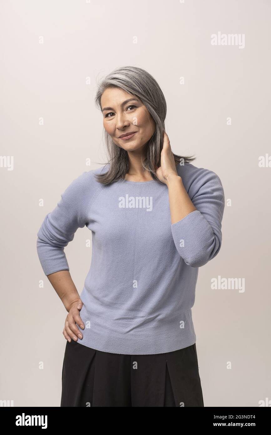 Smiling Asian woman touches her grey hair Stock Photo - Alamy