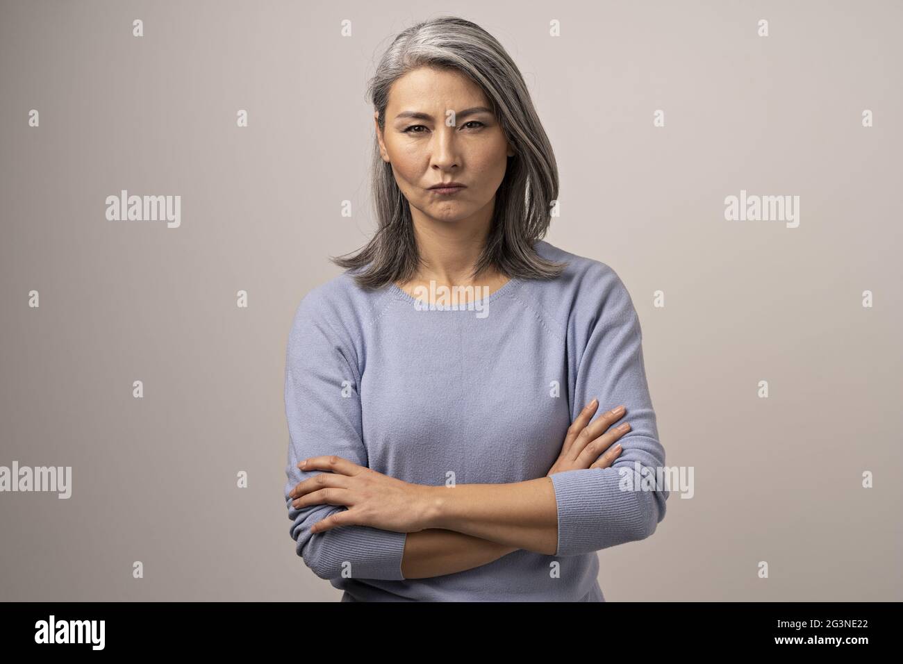Serious Mongolian Woman with Gray Hair Against the Backdrop of Gray. Stock Photo