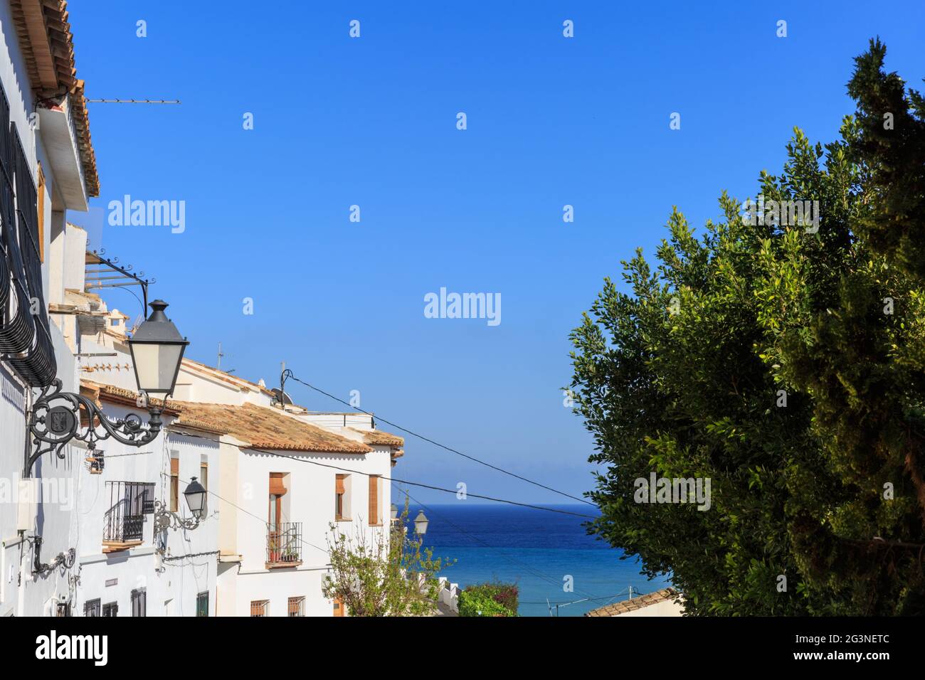 View along a traditional whitewashed Spanish village houses towards the Mediterranean Sea in Sella Old Town, Costa Blanca, Spain Stock Photo