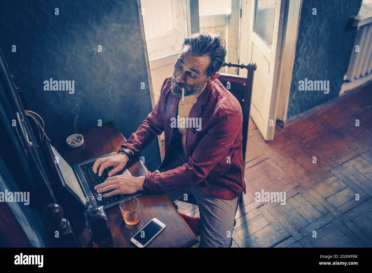 Handsome man works on his laptop smoking and drinking Stock Photo