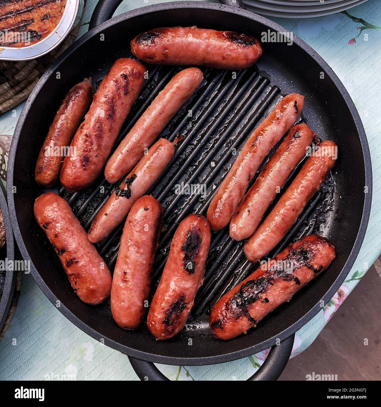 Looking down from above onto a frying pan full of cooked sausages Stock Photo