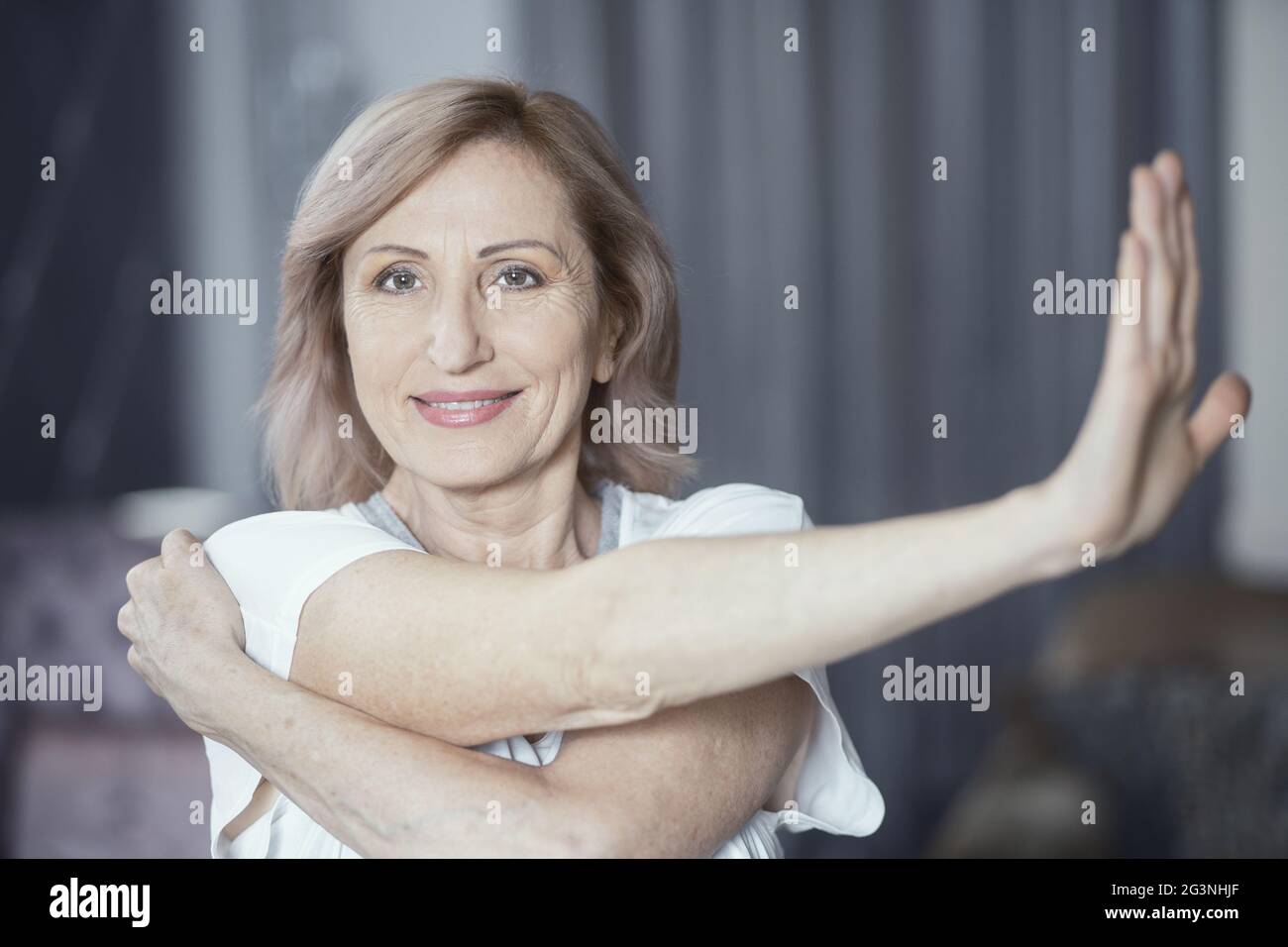 Charming woman is stretching hands before doing yoga exercise Stock ...