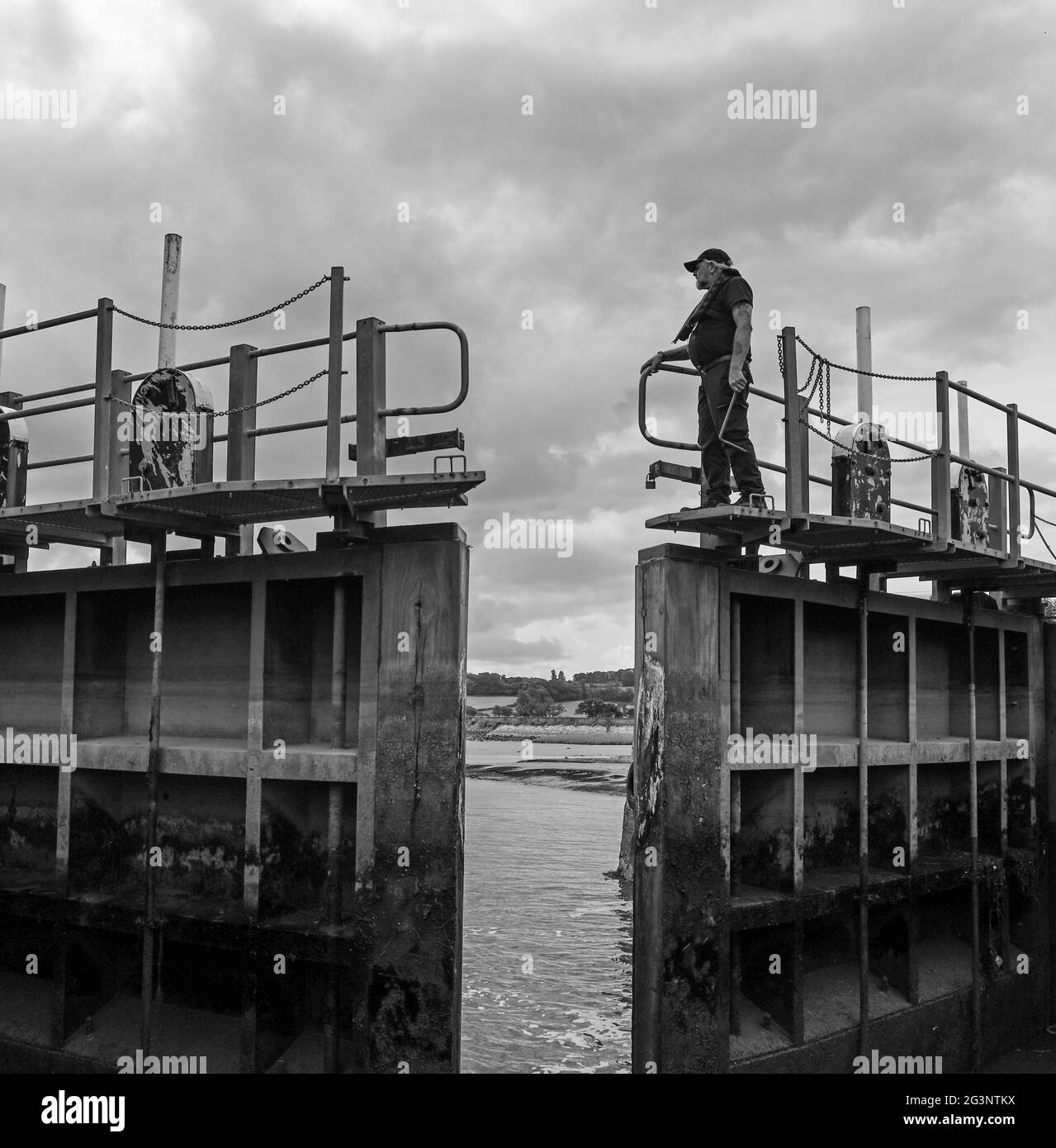 Black and White image of lock keeper on closing gates. Exeter Canal Cruise, up Europe’s oldest working ship canal. Stuart Lines Cruises Stock Photo