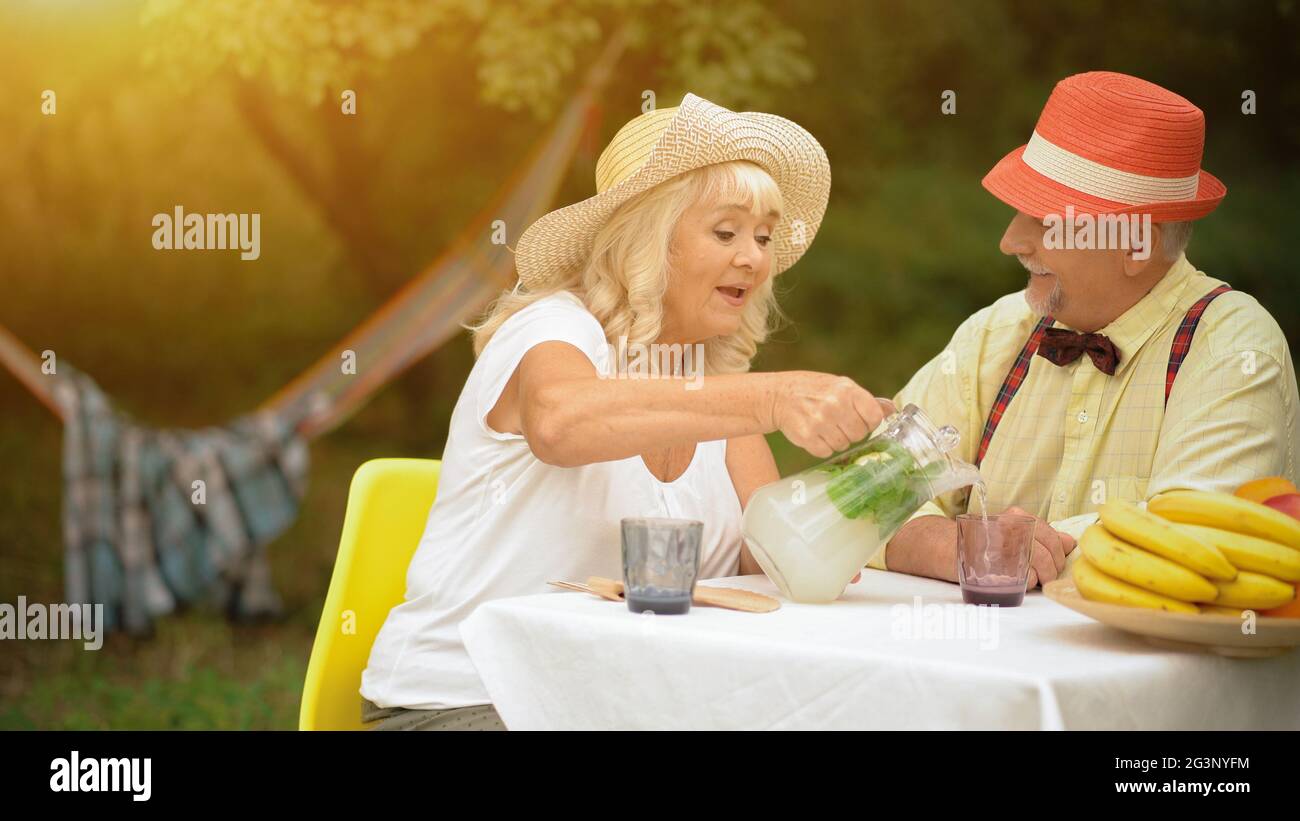 The Old Couple Is Drinking Cold Lemonade In The Summer Garden Stock Photo