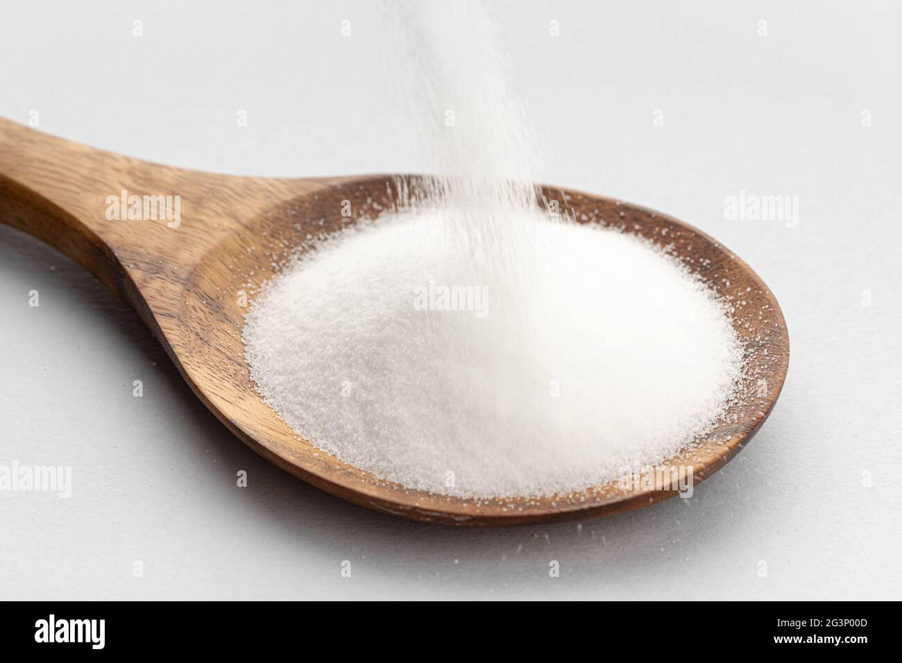 Collagen powder falling into a Wooden Spoon isolated on gray background. Close up Stock Photo