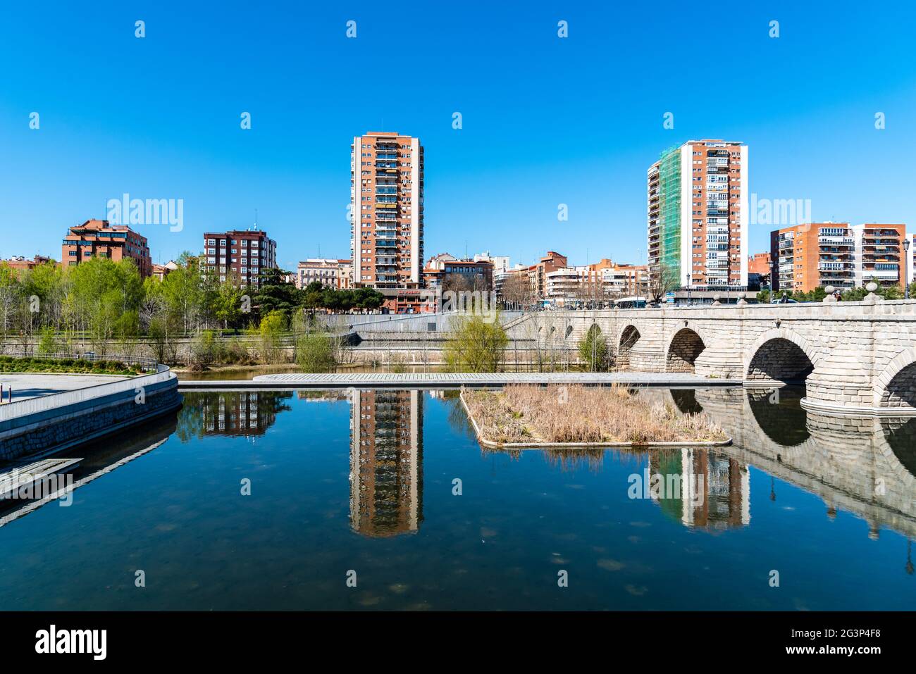 Madrid, Spain - March 14, 2021: Madrid Rio. Bridge of Segovia and Puerta del Angel quarter. Reflections of residential towers on water Stock Photo