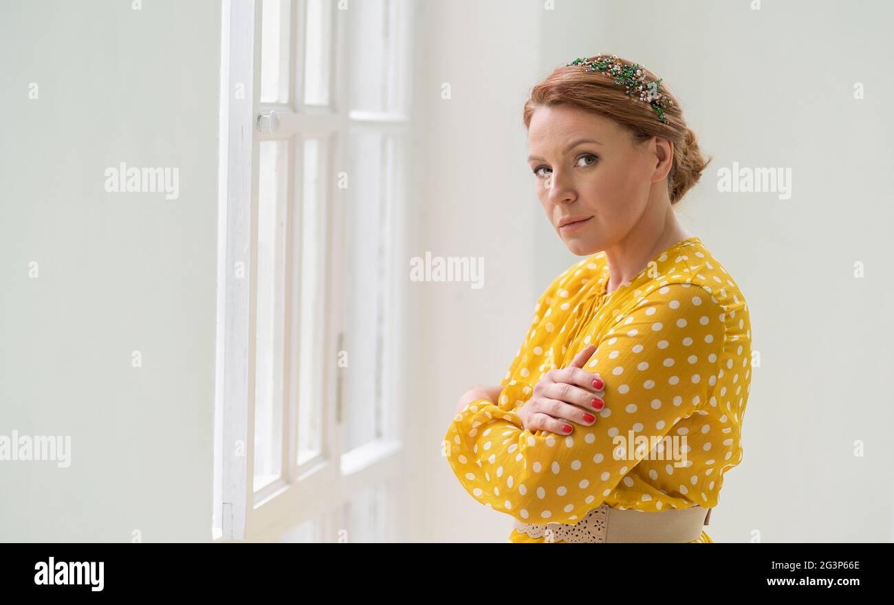 Lonely Red-haired Woman in Yellow Dress Hugs Herself Stock Photo