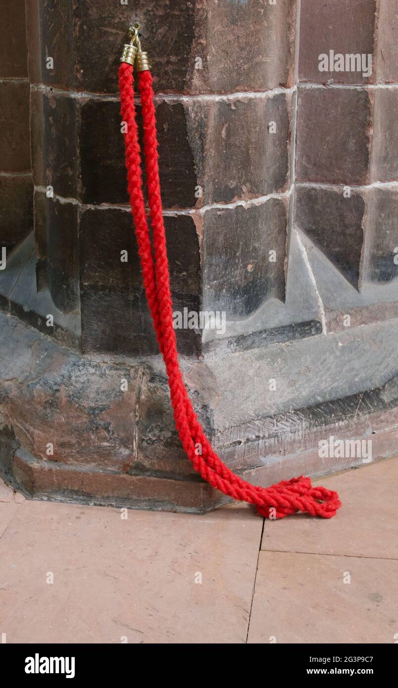 Single red heavy duty rope with brass hooks attached to old weathered