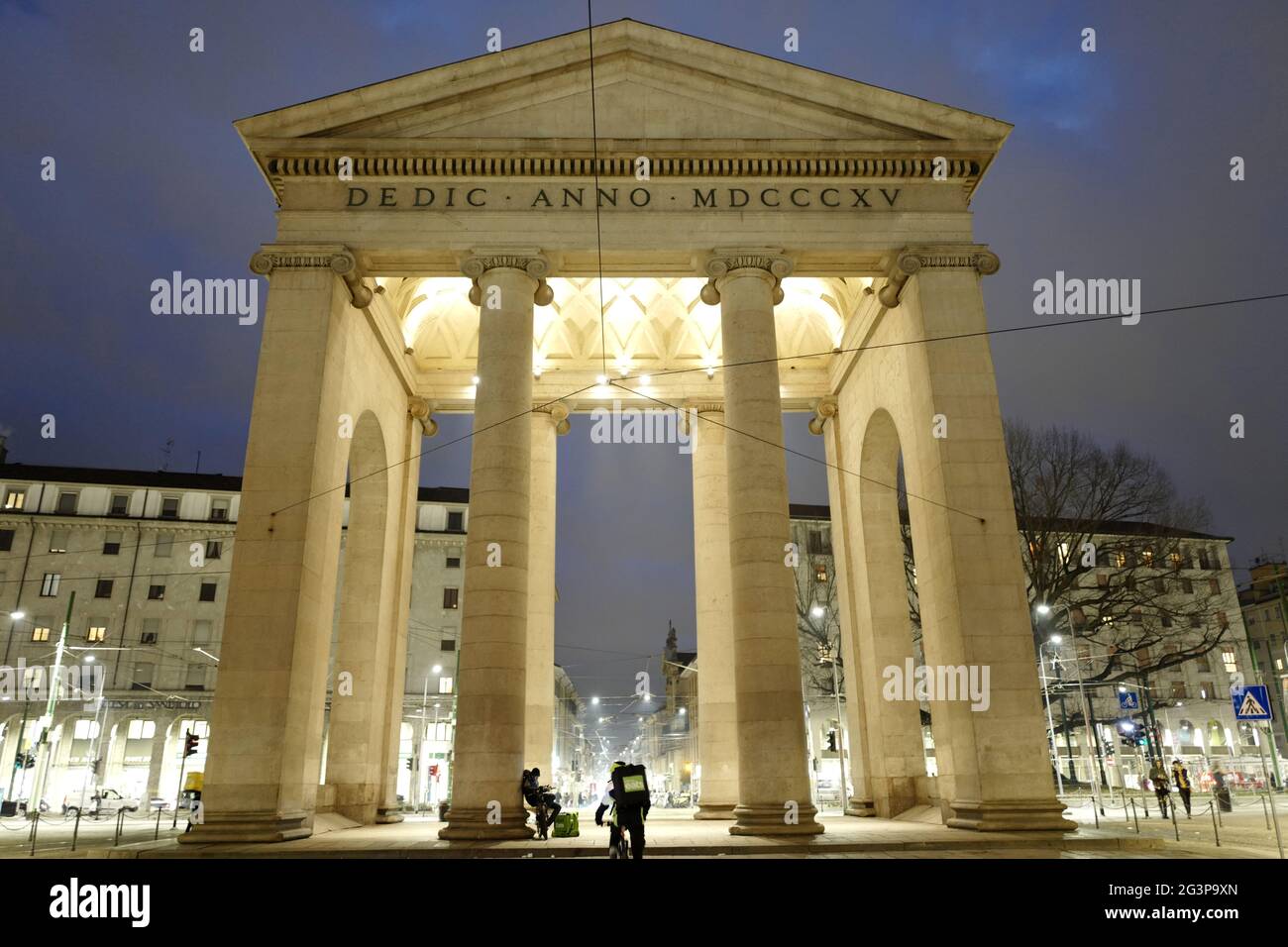 Bikers food delivery waiting at the historical city's entrance gate Porta Ticinese, at night in Milan. Italy Stock Photo