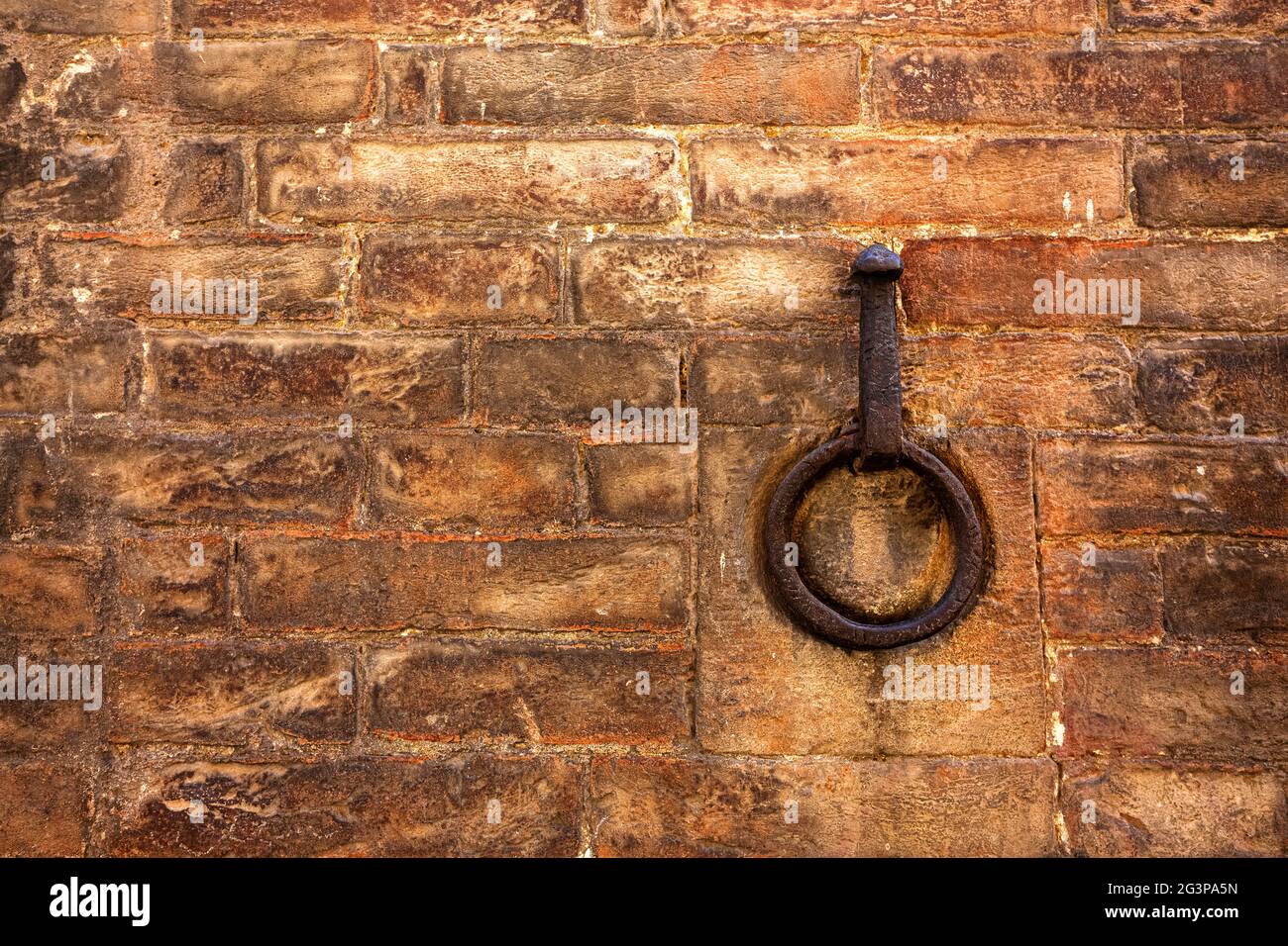A rusty metal ring embedded in a red brick wall. Copy space for text Stock Photo