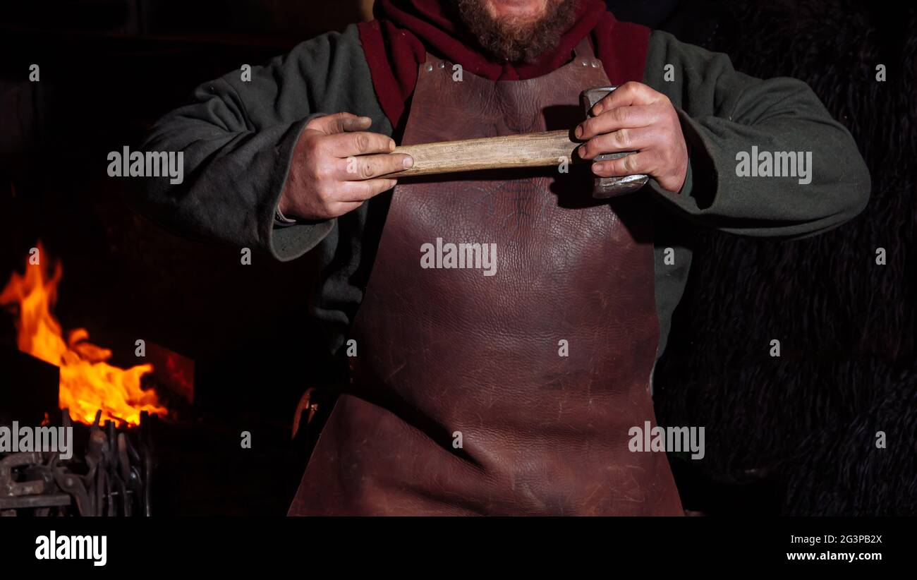 Viking forges weapons and swords in the smithy. A man in a warrior’s