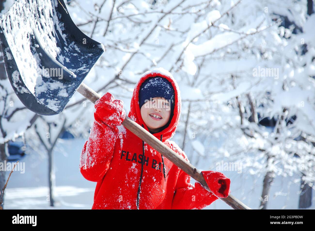 Outdoor winter portrait of a small healthy happy child with a shovel in hand, snow removal Stock Photo