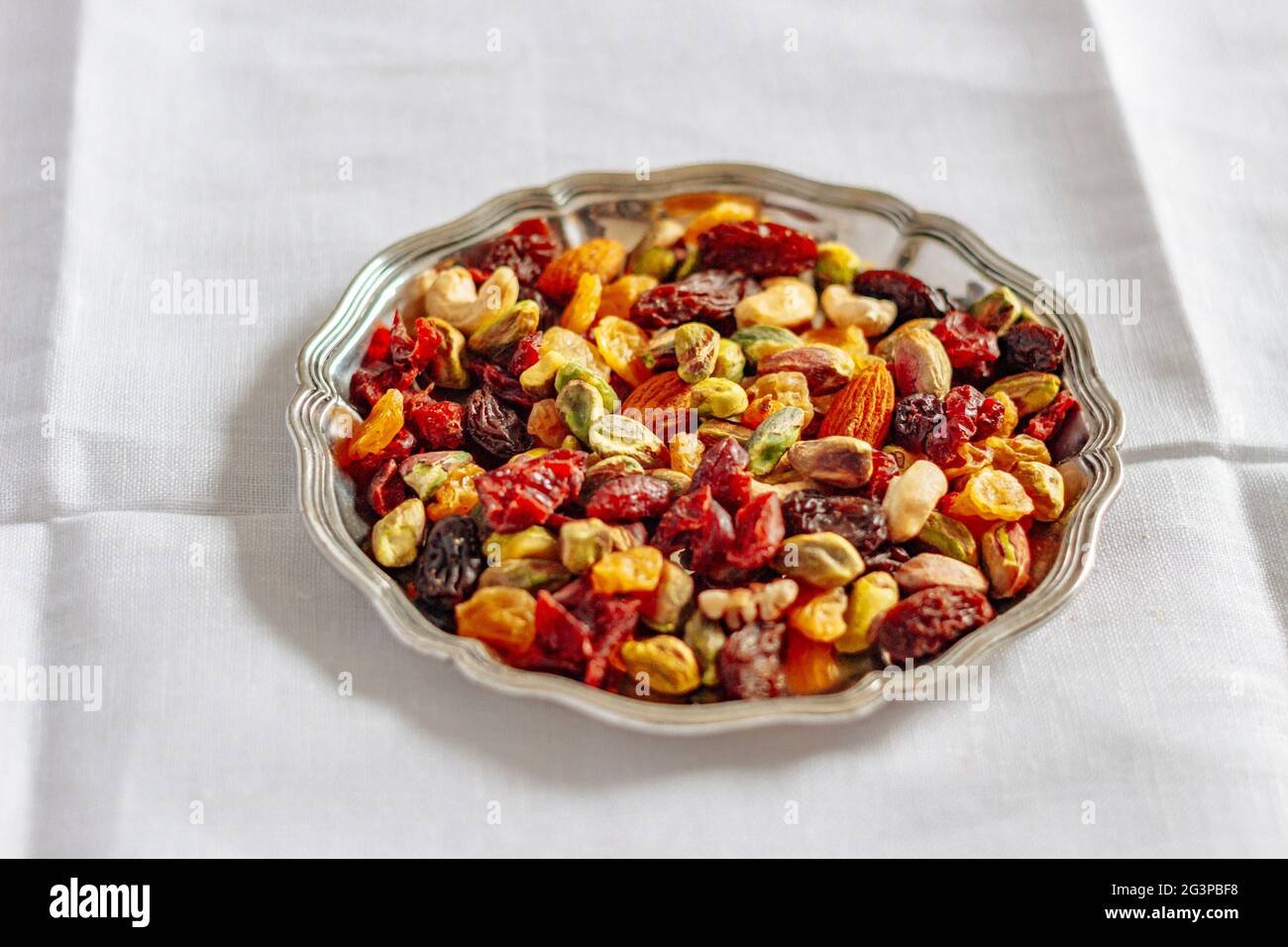 Dried fruit and nuts trail mix, closeup, on silver tray on white Stock Photo