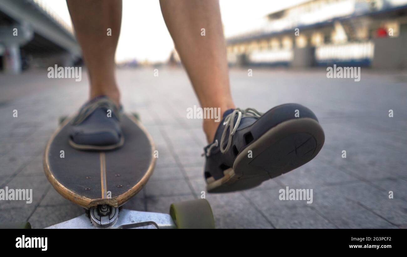 Light-Skinned Mid-Aged Man Gaining Speed On Skateboard Ahead Outdoor. Stock Photo