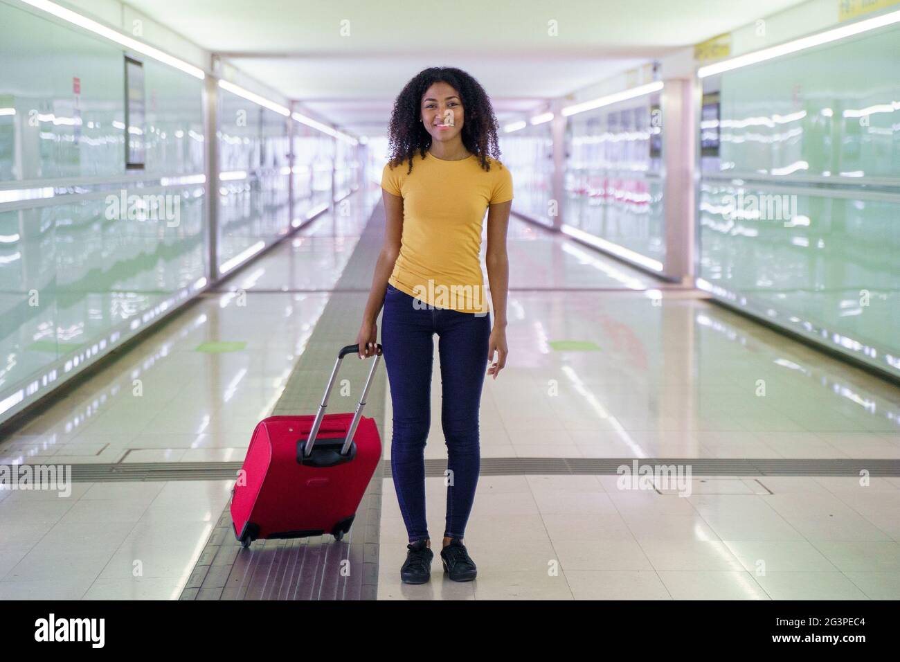 Black woman with cell phone and carryon baggage in station Stock Photo