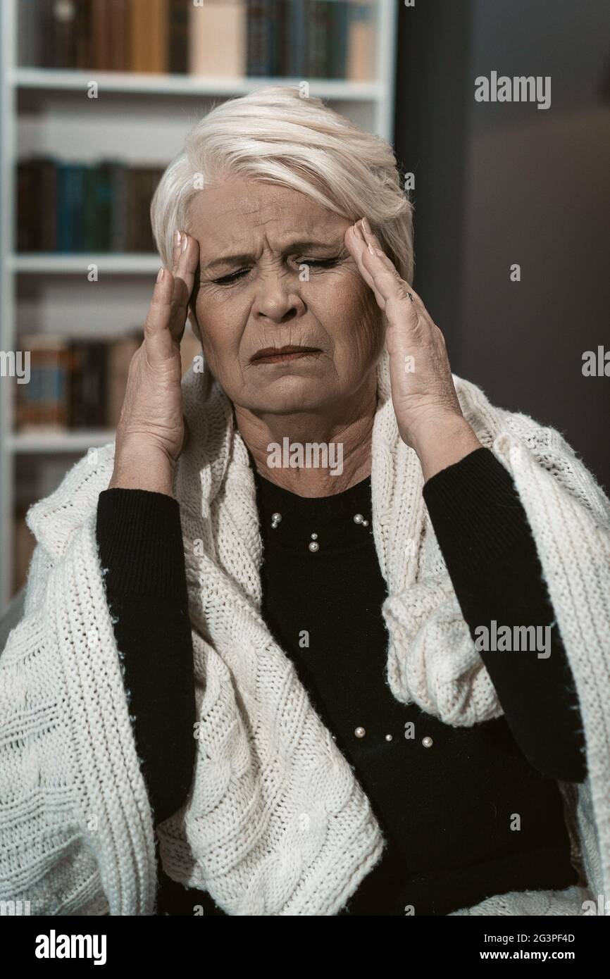 Expressive Elderly Blonde Feels A Headache From Stress Stock Photo
