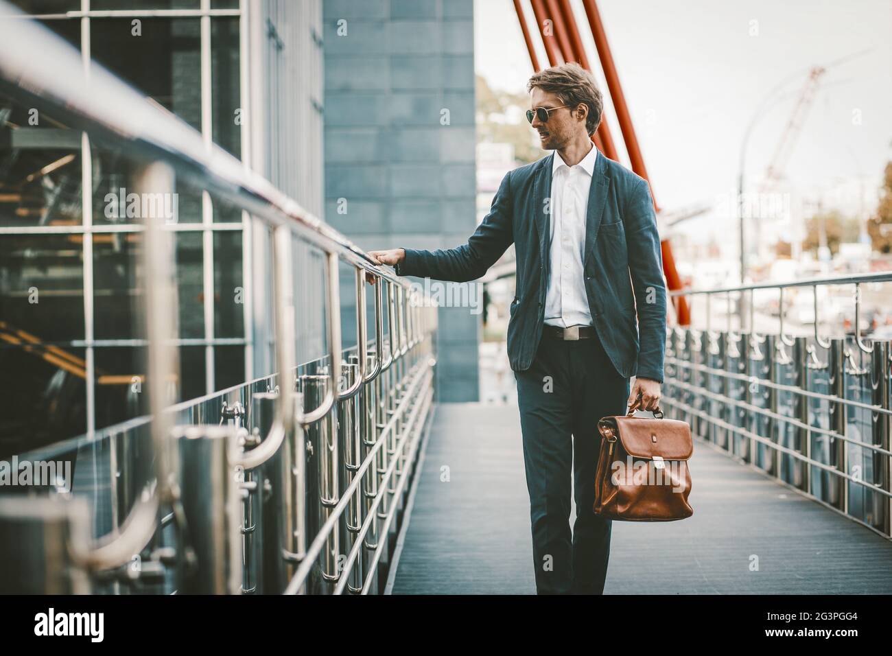 Handsome man standing in blue sute on a bridge of business center Stock Photo