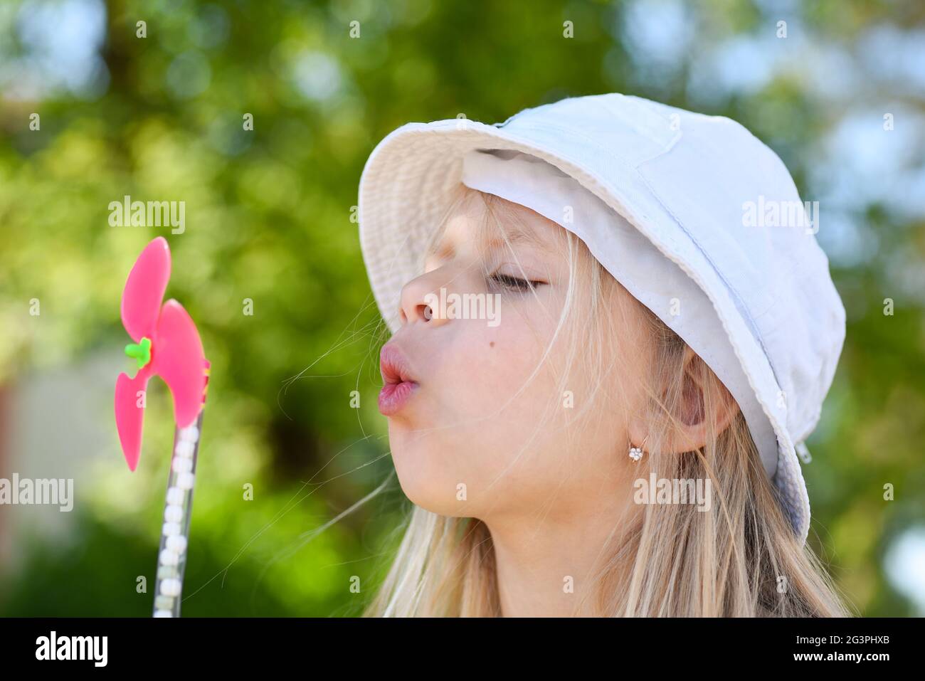 Little girl blowing on a fan in summer Stock Photo - Alamy