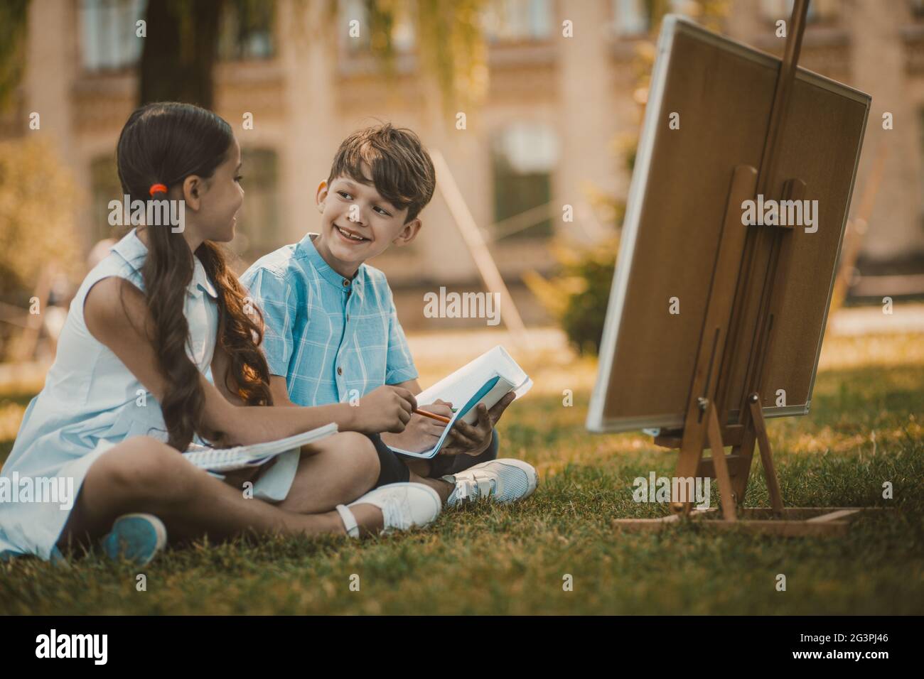 Happy Children Sitting At Green Grass In Park Stock Photo - Alamy