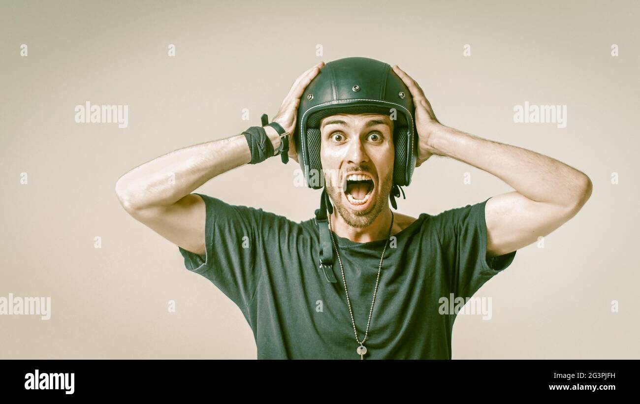 Screaming Man In Helmet Clutching His Head On Grey Back Stock Photo