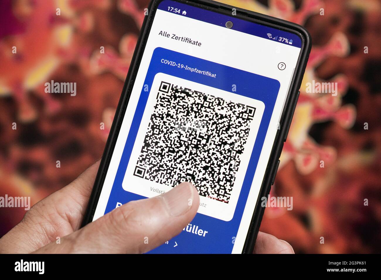 QR-Code, das digitale Impfzertifikat in der CovPass-App des Robert Koch-Instituts auf einem Smartphone bestätigt eine abgeschlossenen Impfung gegen Covid-19. Liegt auf der gelben Internationalen Impfbescheinigung, Impfpass. - ACHTUNG! QR-Code und persönliche Angaben sind unkenntlich gemacht! Stock Photo
