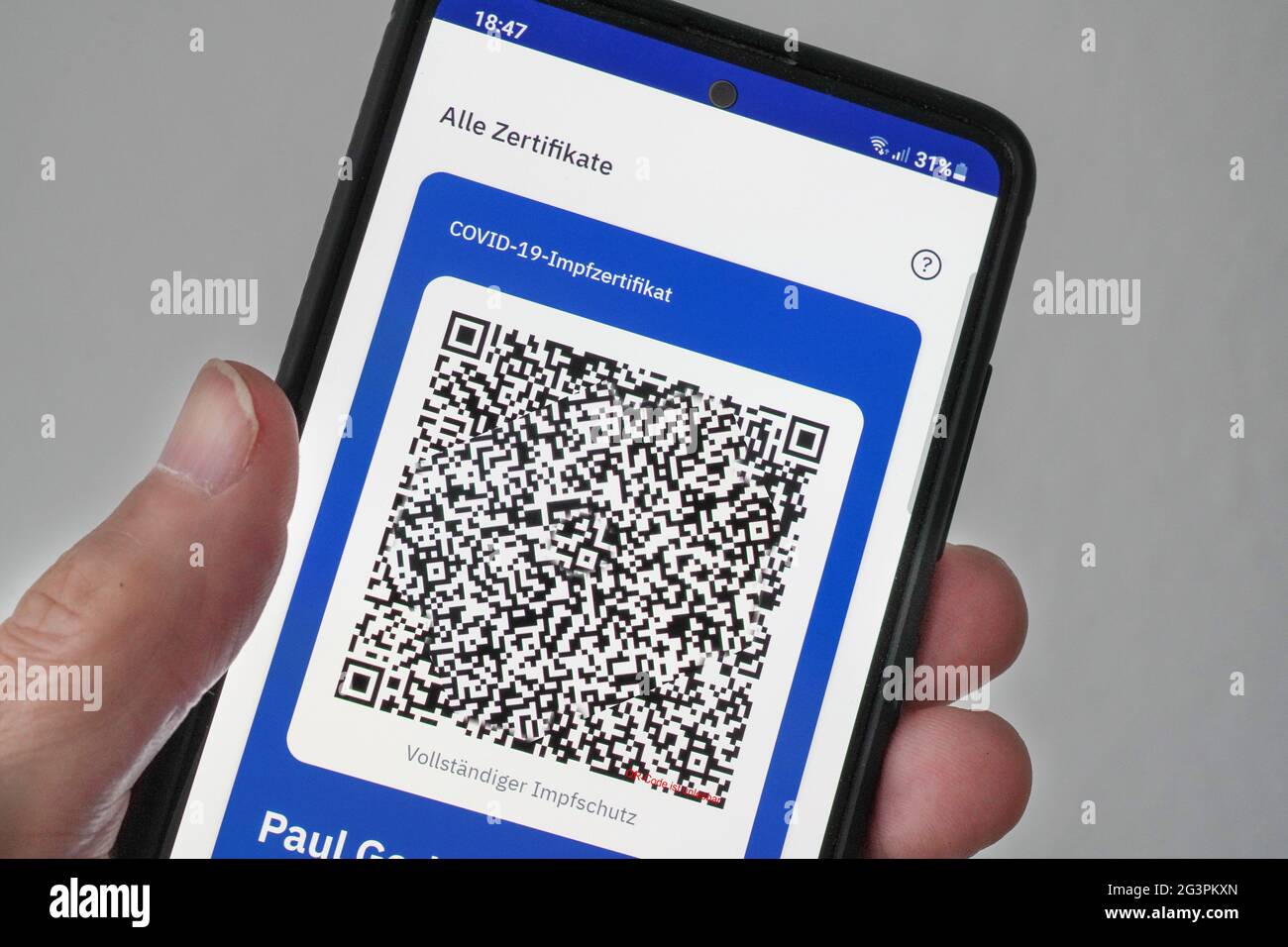 QR-Code, das digitale Impfzertifikat in der CovPass-App des Robert Koch-Instituts auf einem Smartphone bestätigt eine abgeschlossenen Impfung gegen Covid-19. Liegt auf der gelben Internationalen Impfbescheinigung, Impfpass. - ACHTUNG! QR-Code und persönliche Angaben sind unkenntlich gemacht! Stock Photo