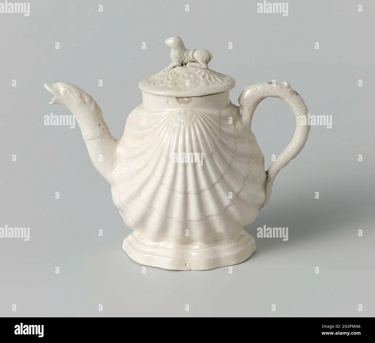 Teapot of white stoneware with salt glaze; Whellow ware. Teapot of white stoneware with salt glaze. The stomach of the pot has the shape of a double shell. The spout is bent and has the head of a fish as a mouth. The ear is C-shaped and has the shape of a dolphin. The lid has a lying dog or lion as a button. Stock Photo