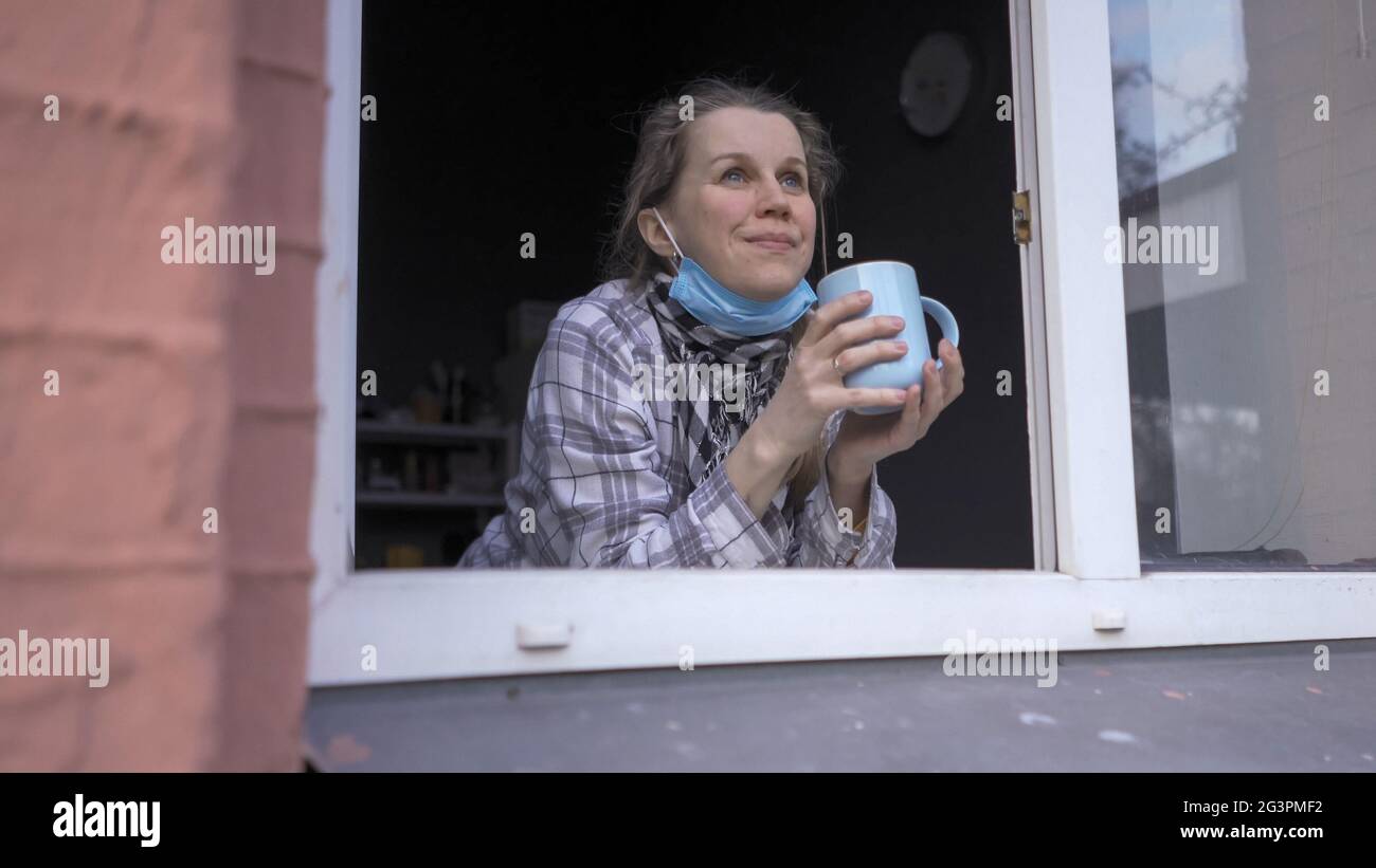 Woman In Self-Isolation Drinks Tea Near Opened Window Stock Photo