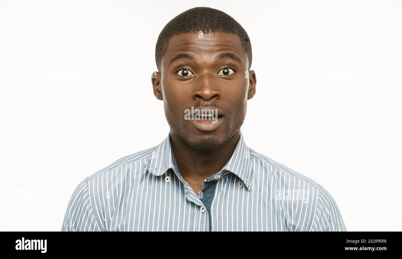 Surprised Afro-American businessman. Young Amazed man looks at camera with opened mouth and astonished eyes. Cut out portrait on Stock Photo