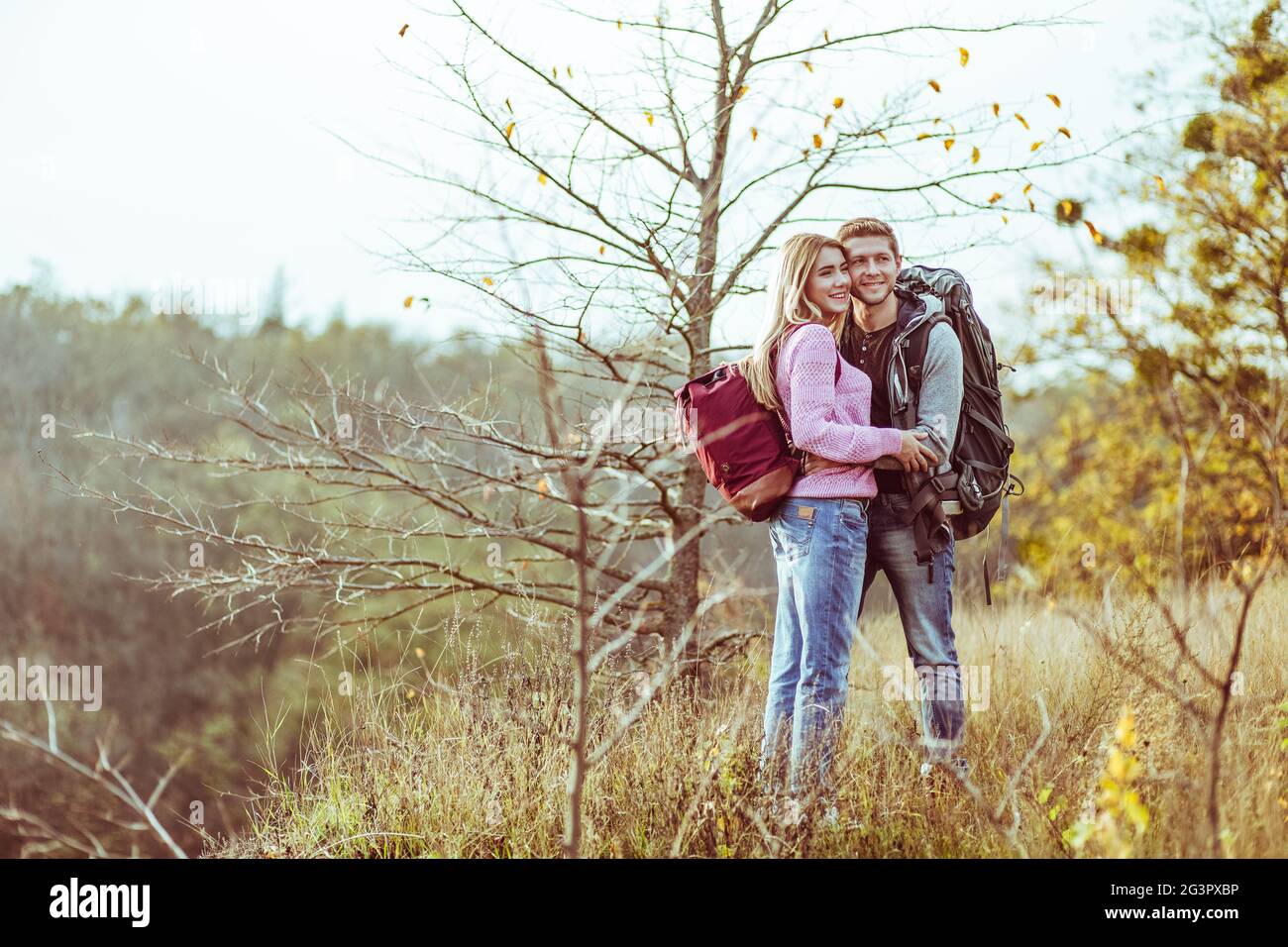 Hugs on top of the hill. Couple of lovers tourists cuddling while looking at the camera. Copy space at left side Stock Photo