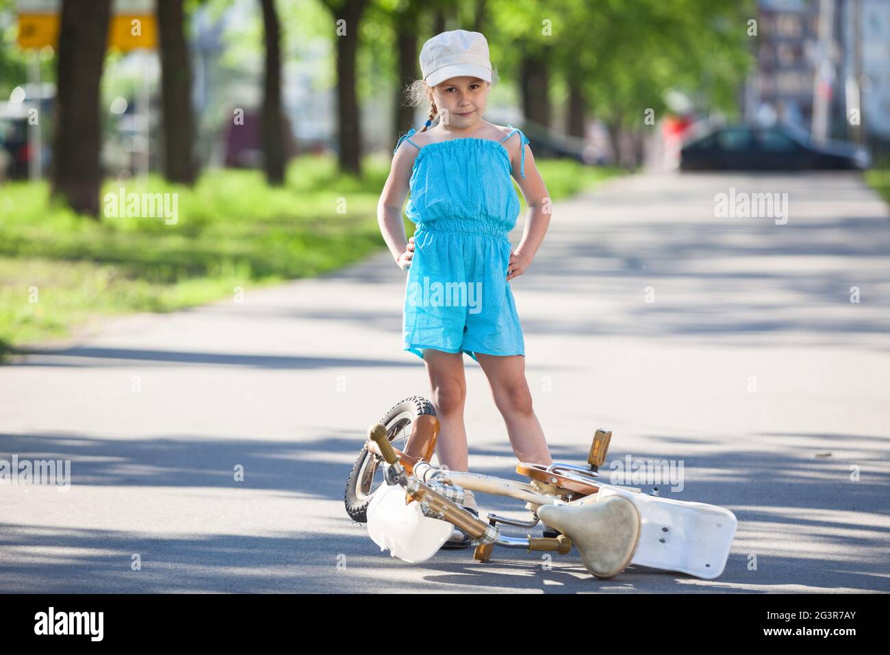 Caucasian preschool girl portrait with bicycle lying on asphalt road Stock Photo