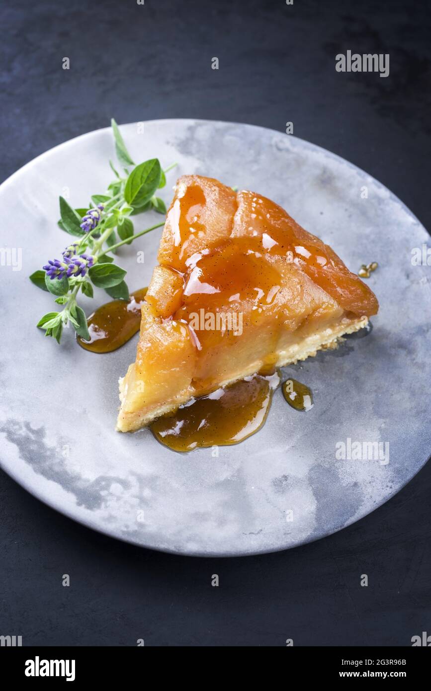 Traditional French tarte tatin with apples and vanilla offered as close-up on a modern design plate with rustic background Stock Photo