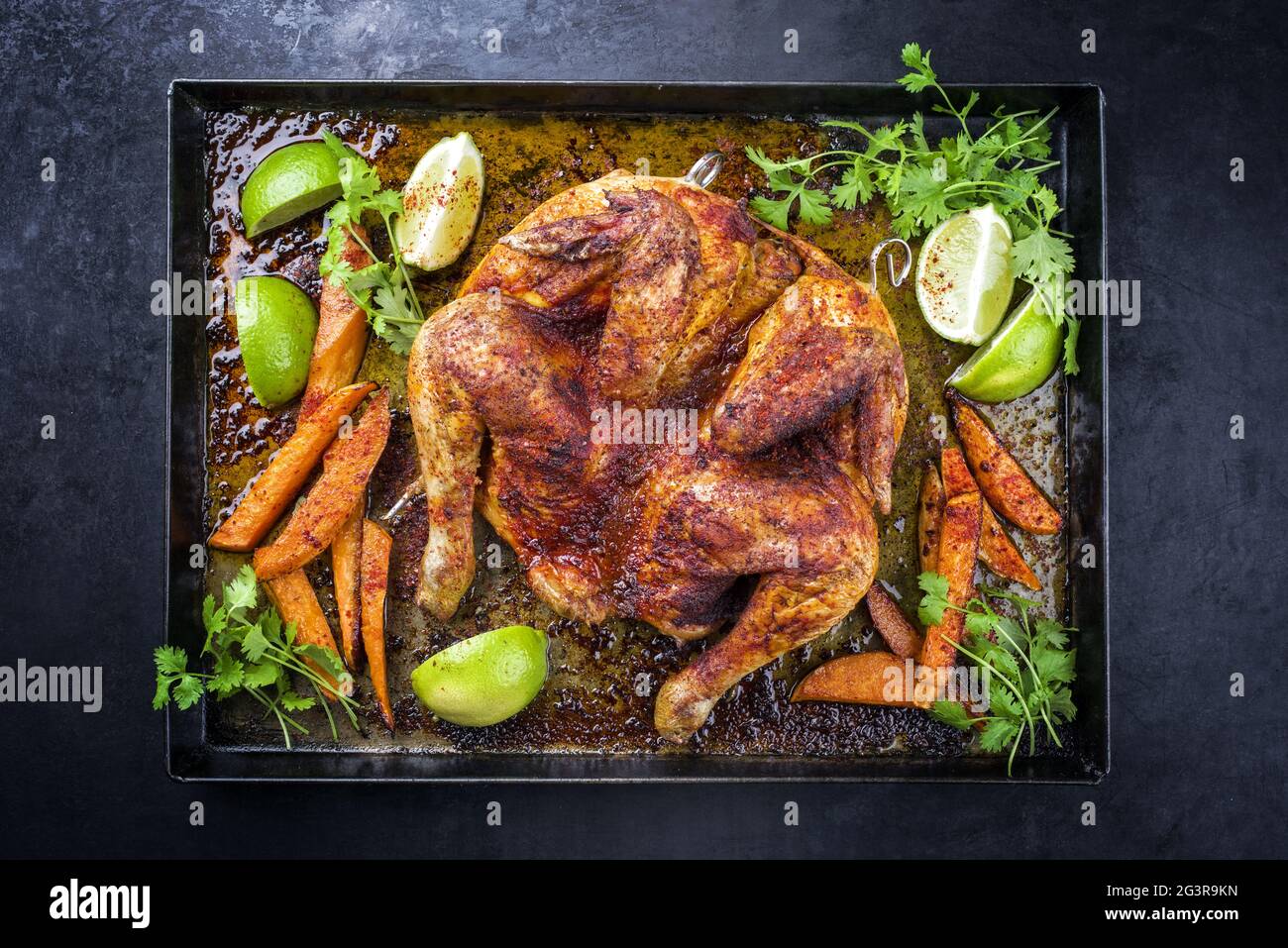 Traditional barbecue spatchcocked chicken al mattone chili with sweet potato chips and limes offered as top view on an old rusti Stock Photo