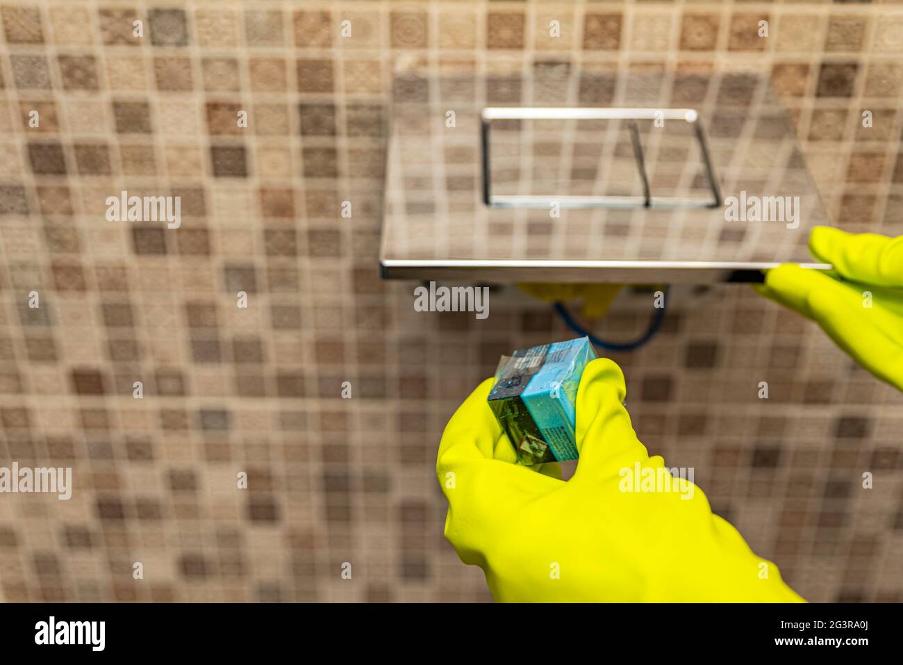 Toilet cubes cleaner in hand. A hand lowers a disinfectant cube into