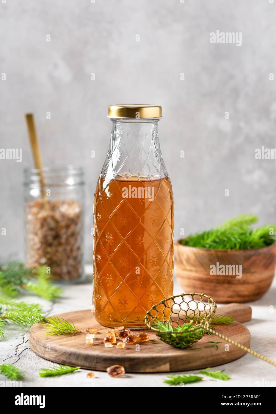 Bottle of homemade syrup made from young spruce tips and nature sugar on the wooden cutting board. Stock Photo