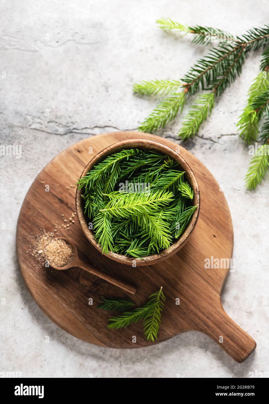 Young green spruce tips in a wooden bowl  and spoon with nature sugar. Ingredient to prepare homemade herbal syrup against cough or honey. Stock Photo