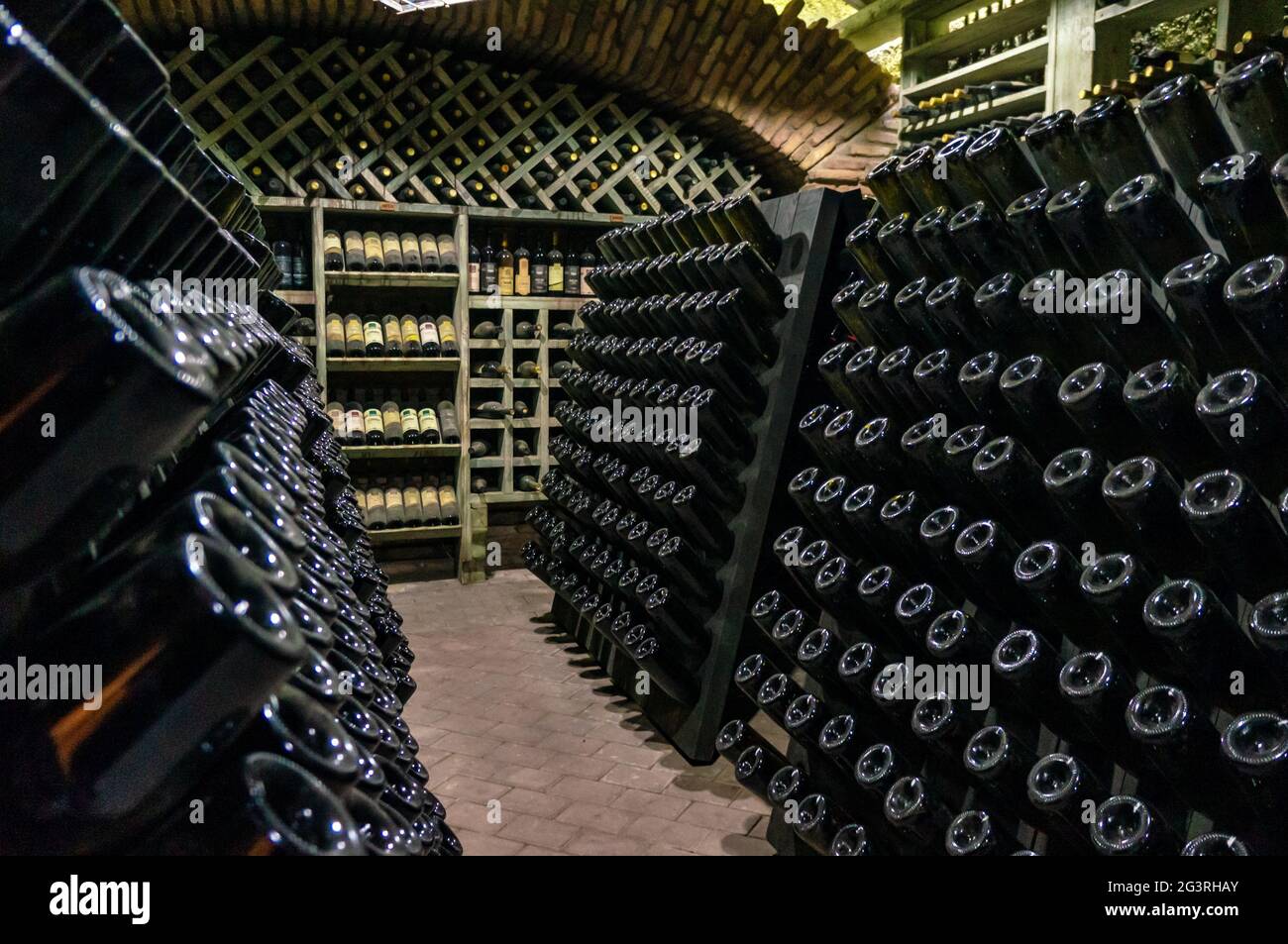 Wine cellar with wine bottles. Old wine bottles covered with dust and cobwebs are in the wine cellar of winery. Alcohol drink vi Stock Photo