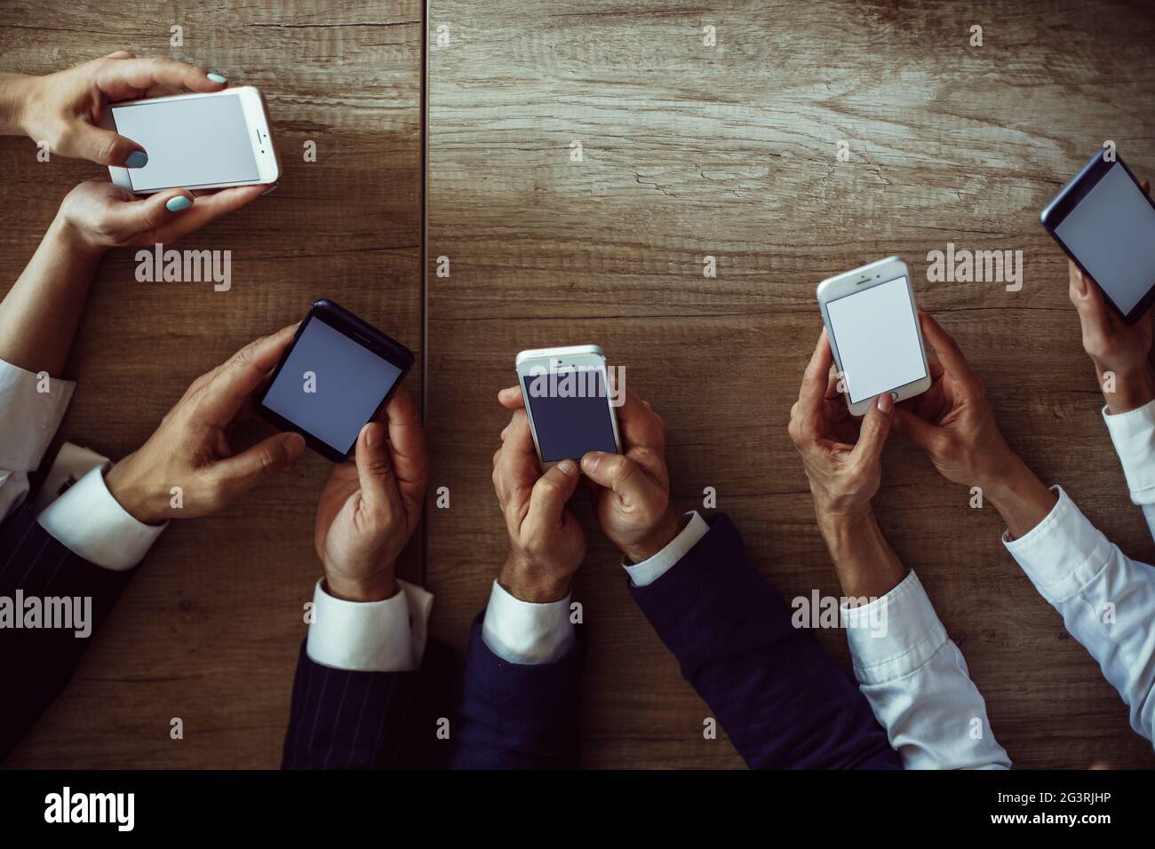 Office workers holds mobile phones. Close up shot of human hands using smartphones. High angle view. Toned image. High quality p Stock Photo