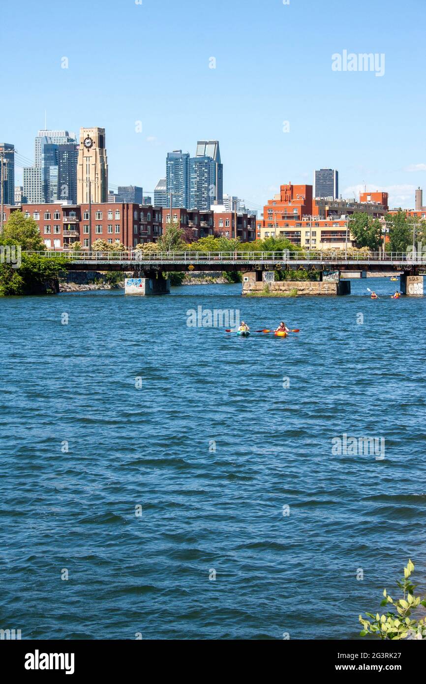 View of Downtown Montreal and the Atwater Market from the Lachine Canal with boats and kayaks floating along Stock Photo