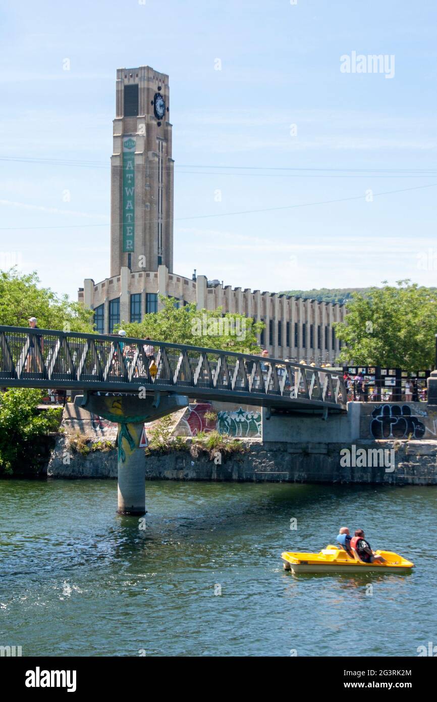 A pedalo passes under the Atwater Market footbridge, with Montreal's famous market in the background Stock Photo
