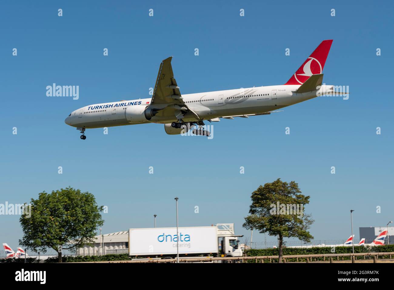 Turkish Airlines Boeing 777 airliner jet plane TC-LJH  on finals to land at London Heathrow Airport, UK, over A30 road and catering business lorry Stock Photo